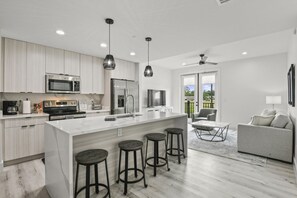 A modern kitchen with a large island, bar stools, and stainless steel appliances.