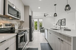 A modern kitchen with stainless steel appliances, a built-in oven, and a large island with a sink. - Brand New 1 Bedroom Condo-Luxurious Waterfront Pool-Sleeps 4 (Gulfport)