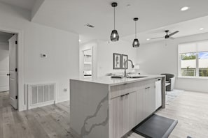 Eine moderne Küche mit Kochinsel, Pendelleuchten und Deckenventilator.
