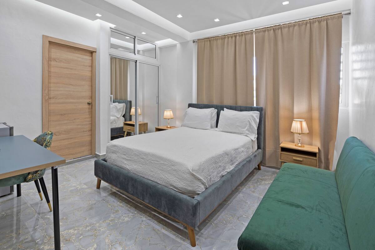 Een slaapkamer met een bed, een bureau, een stoel en een groene bank.