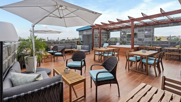 An outdoor patio with wicker furniture, stone walls, and umbrellas.