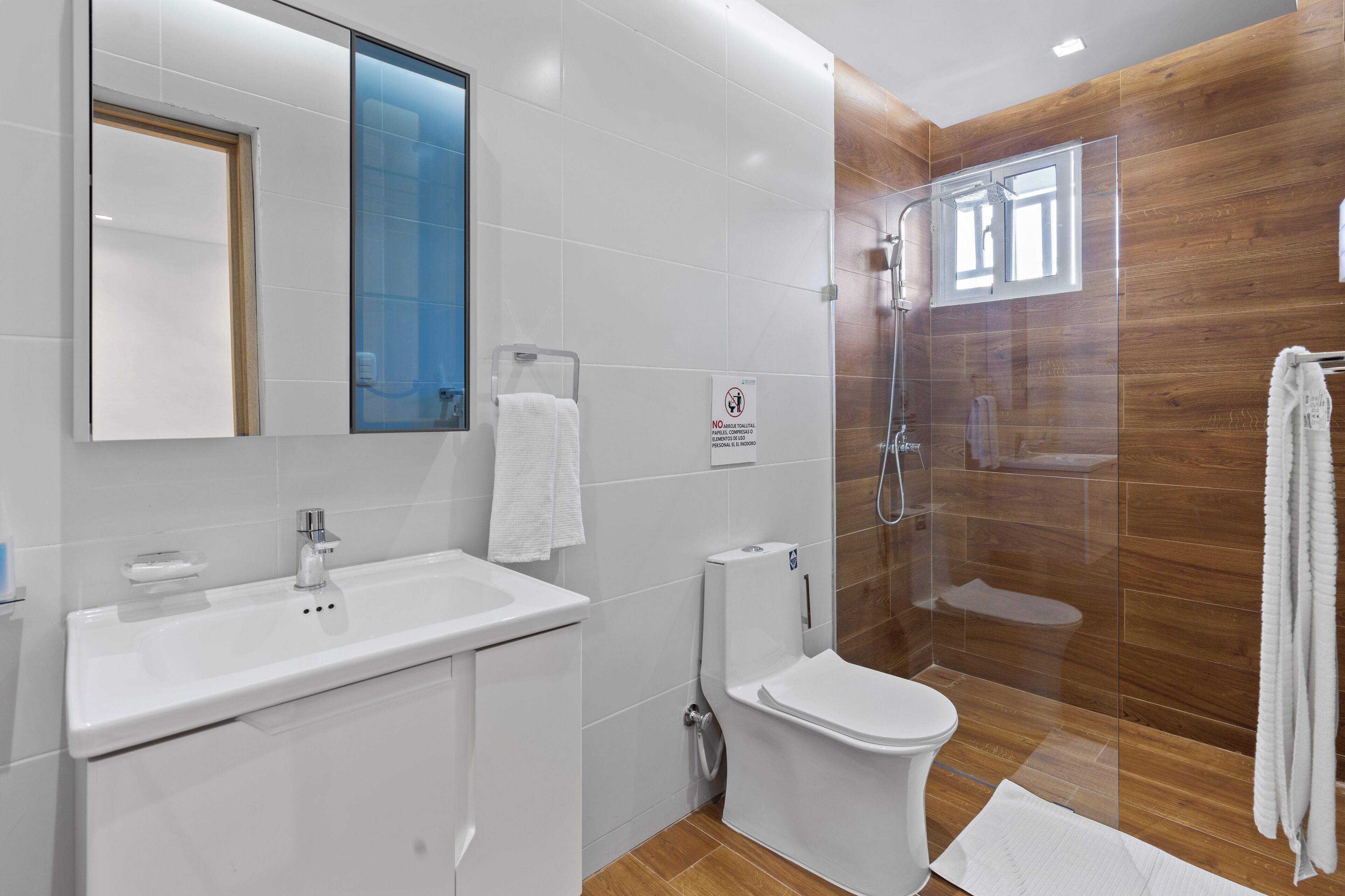 A modern bathroom with a white sink, toilet, and glass shower enclosure.