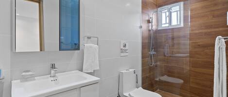 A modern bathroom with a white sink, toilet, and glass shower enclosure.