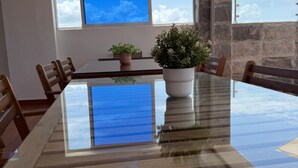 A dining table with chairs, a potted plant, and a view of the sky through a window.