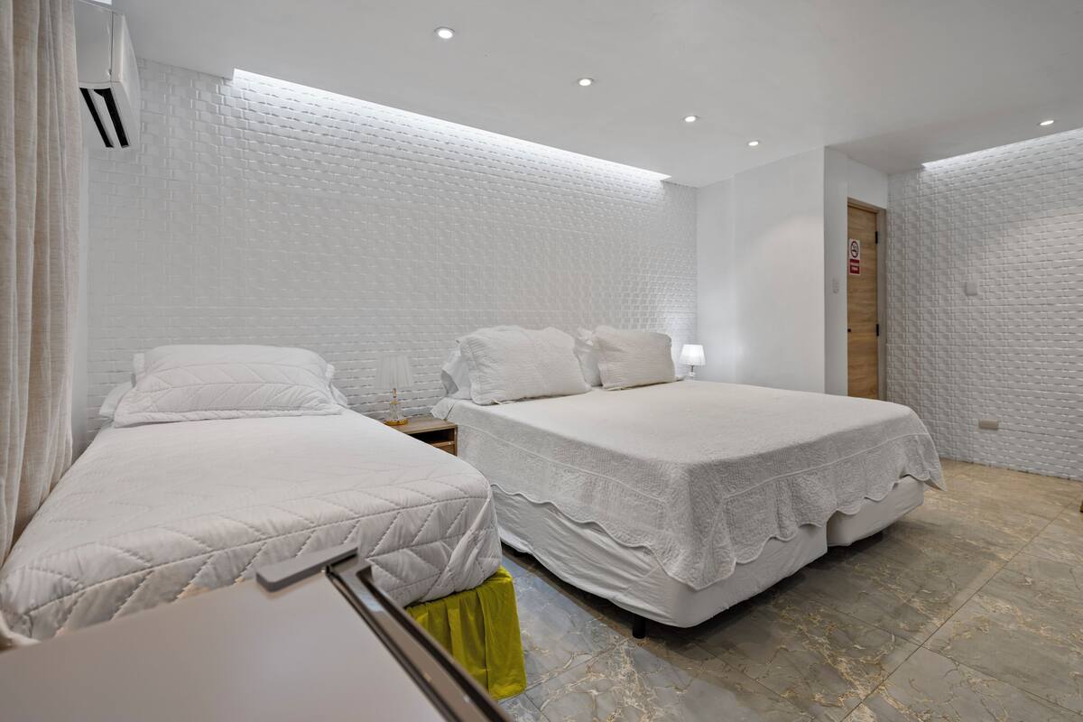 Een moderne hotelkamer met twee bedden, een klein nachtkastje, een bedtafel en een deur met een bordje.