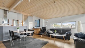 Ein modernes Wohnzimmer mit Essbereich, einem schwarzen Ledersofa, einem Couchtisch und einer Karte an der Wand.