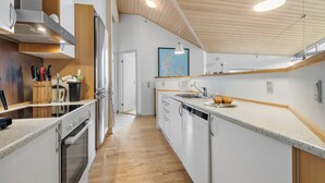 Eine moderne Küche mit Kochinsel, Edelstahlgeräten und Holzelementen.