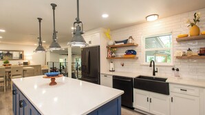 A modern kitchen with a central island, white cabinetry, and a black sink. - Gorgeous Modern Lakeside Getaway in Gun Barrel City (Gun Barrel City)