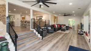 A spacious living area with a staircase, a ceiling fan, and a large window. - Gorgeous Modern Lakeside Getaway in Gun Barrel City (Gun Barrel City)