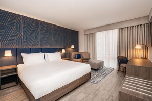 A modern hotel room with a large bed, a sofa, a desk, and a chair. - Hyatt Place Leeds (Leeds)