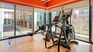 A gym with cardio equipment and large windows overlooking a cityscape. - Hyatt Place Leeds (Leeds)