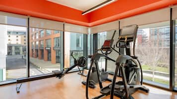 A gym with cardio equipment and large windows overlooking a cityscape.