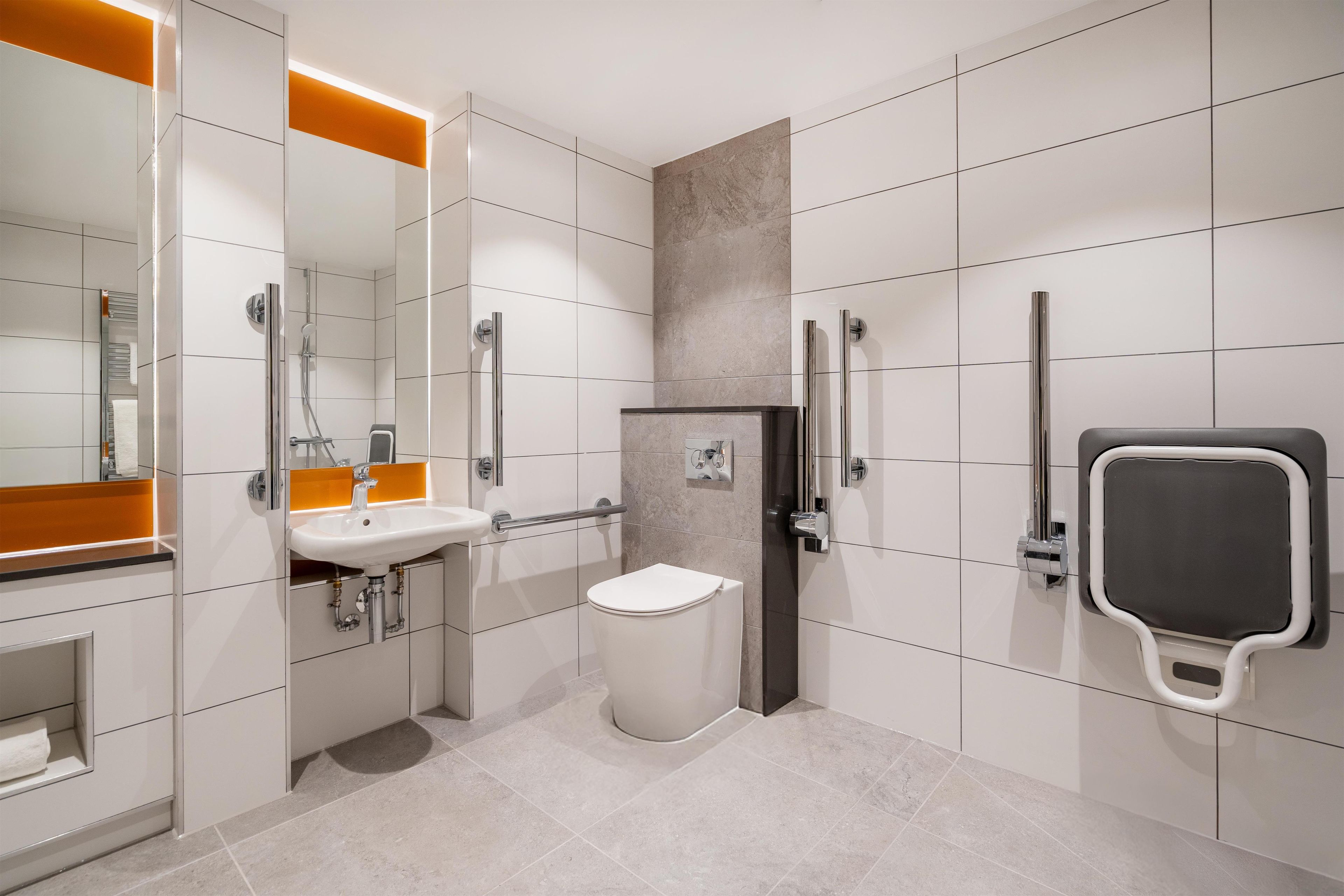 Un baño moderno con lavamanos, inodoro y zona de ducha blancos.