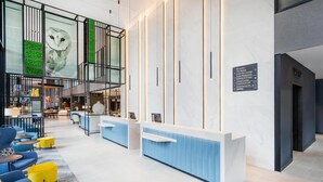A modern hotel lobby with a reception desk, seating area, and a large wall mural. - Hyatt Place Leeds (Leeds)