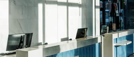 A modern reception desk with a marble finish, a computer, and a phone.