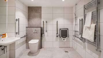A modern bathroom with a toilet, bidet, and hand dryer.