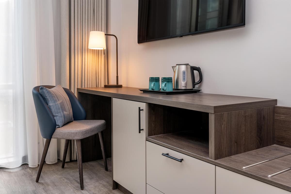 A modern kitchenette with a flat-screen TV, a kettle, and two mugs on the counter.
