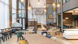 A modern restaurant with high ceilings, exposed brick walls, and a mix of seating options including tables and booths. - Hyatt Place Leeds (Leeds)