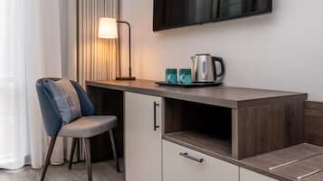 Una kitchenette moderna con estufa integrada, un televisor de pantalla plana montado arriba y una silla con cojín estampado.