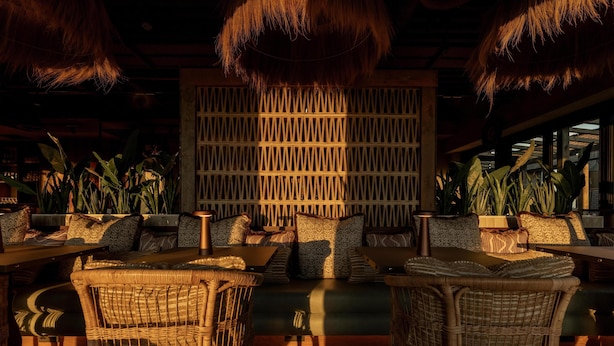 A cozy lounge area with wicker furniture, a patterned wall, and potted plants. - Hyatt Place Leeds (Leeds)