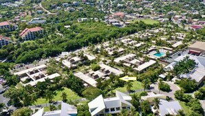 An aerial view of a resort with multiple bungalow-style accommodations, a central pool, and lush greenery. - Your tropical studio steps from the beach. (St Thomas)