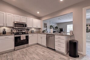 A modern kitchen with white cabinets, stainless steel appliances, and a granite countertop. - Charming 4-Bedroom North Scottsdale (Scottsdale)