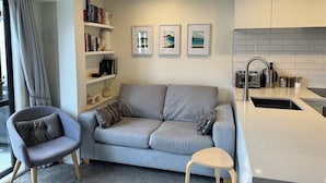 Un salón moderno con un sofá gris, una mesita redonda y una estantería.