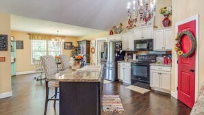 A spacious kitchen with a central island, stainless steel appliances, and a red door.