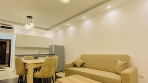 A modern living room with a beige sofa, a wooden coffee table, and a dining area with a table and chairs. - Go Egypt Luxe Living Apartments (Hurghada)