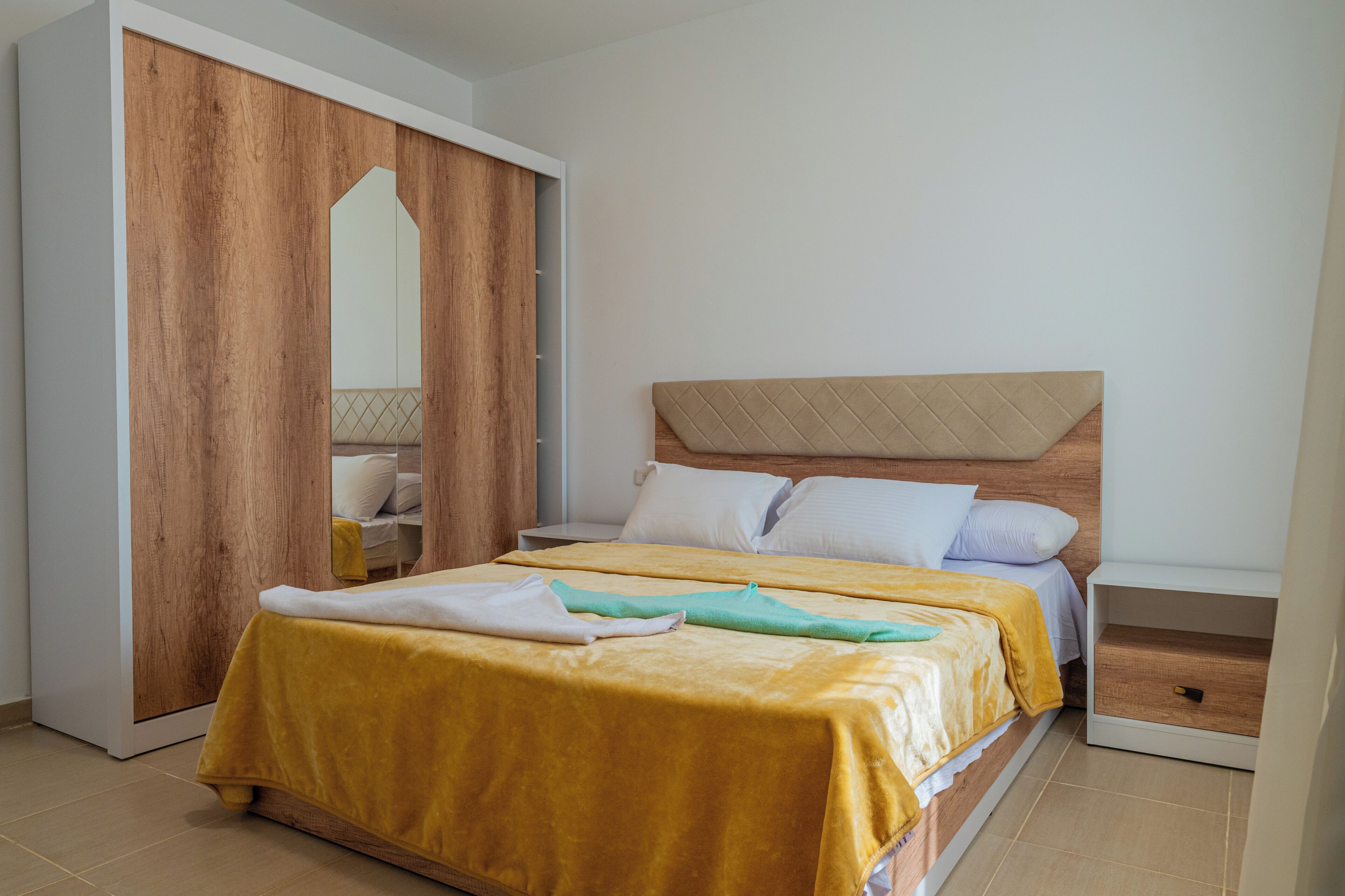 Un dormitorio con cama, armario de madera y mesita de noche.