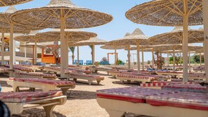 A beachside area with rows of sun loungers and thatched umbrellas. - Go Egypt Luxe Living Apartments (Hurghada)