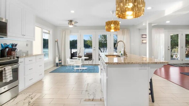 A modern kitchen with white cabinetry, a large island, and pendant lighting. - Luxurious large 3bd/2ba Home with Dock with beautiful sunset views (Eatonton)