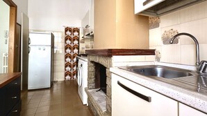 A kitchen with a stone fireplace, a sink, a refrigerator, and a washing machine. - P032 - Porto Recanati, sky-land 100 meters from the sea (Porto Recanati)