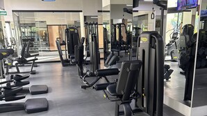 Un gimnasio con diversos equipos de ejercicio, incluyendo cintas de correr, máquinas de pesas y mancuernas.