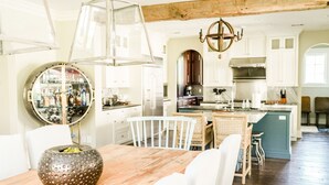 A spacious kitchen with white cabinetry, a wooden dining table, and a large island with seating.