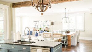 A modern kitchen with a large island, built-in appliances, and a rustic ceiling beam.
