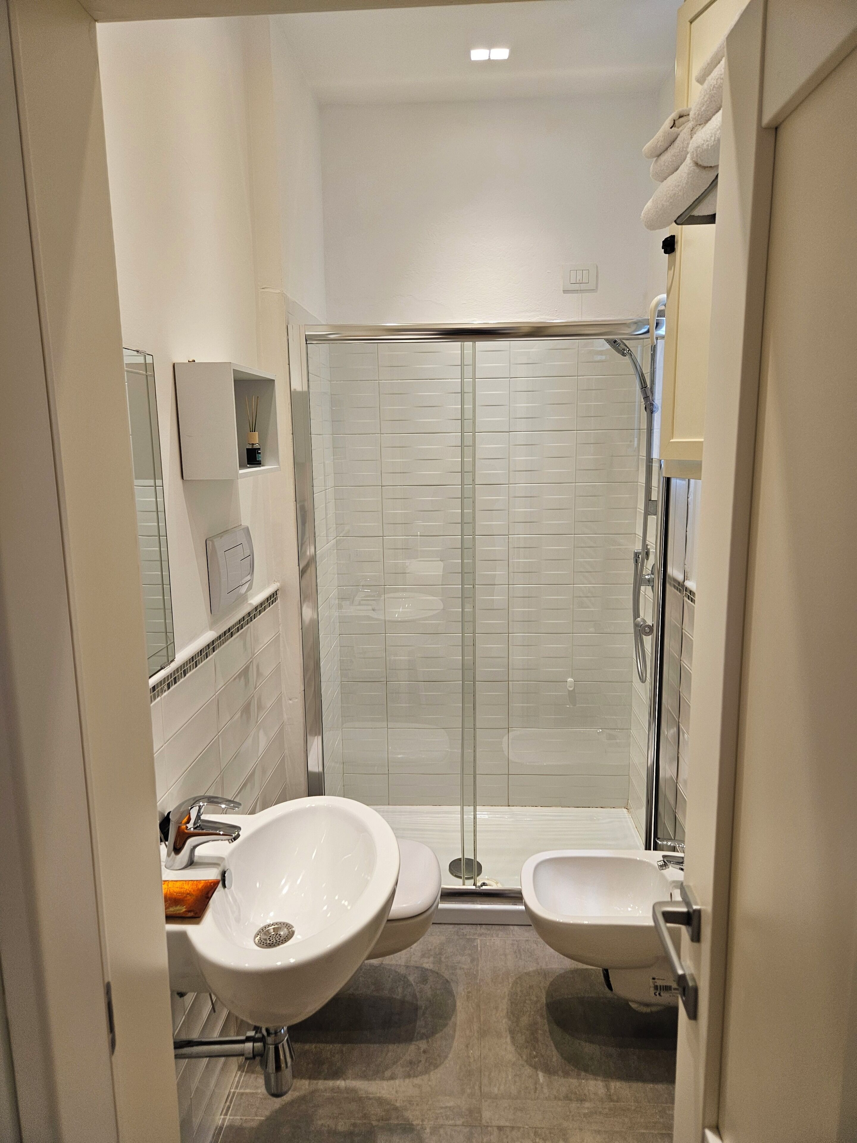Une salle de bain moderne avec une douche à parois de verre, deux lavabos et des toilettes.
