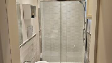 Une salle de bain moderne avec une douche à parois de verre, deux lavabos et des toilettes.