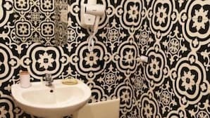 A bathroom with a white pedestal sink, a bidet, and a toilet. The walls have a black and white patterned wallpaper. - Napul'è (Naples)