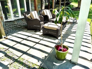 Eine überdachte Terrasse mit Korbmöbeln und einem Blumentopf.