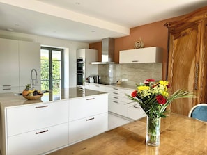 Eine moderne Küche mit weißen Schränken, einem Holzespeisetisch und einer Blumenvase.