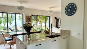 Une cuisine moderne dotée d’un grand îlot central, d’une horloge et offrant une vue sur l’extérieur.