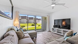 A modern living room with a sofa, TV, and a ceiling fan.