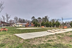 Un parque con un área de juegos, mesas para picnic y una zona de hormigón con bancos.