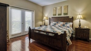 Un dormitorio con una cama de madera, dos lámparas de noche, una mesita de noche y un ventanal corredero.