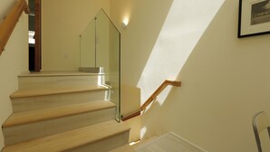 Een trap met houten treden en een glazen balustrade, die naar een verdieping leidt.