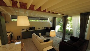 Een moderne zithoek met een bank, een eettafel en een keuken op de achtergrond.
