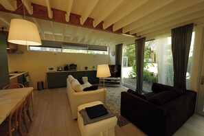 A modern living room with a sofa, a dining table, and a kitchen area.