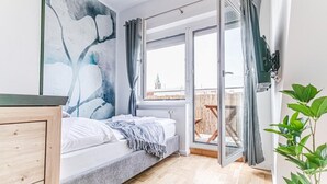 Une chambre avec un lit, une fenêtre, un balcon et une plante.