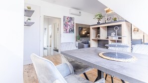 Un espace de salle à manger moderne avec une table grise, des chaises rembourrées et un escalier en bois.